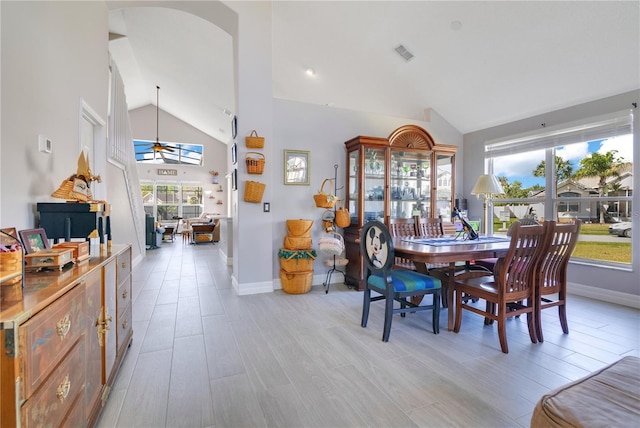 dining space with arched walkways, high vaulted ceiling, visible vents, baseboards, and light wood-type flooring