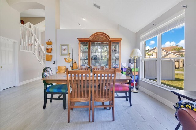 dining area featuring stairs, light wood-type flooring, visible vents, and baseboards