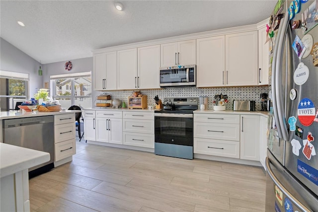 kitchen featuring tasteful backsplash, white cabinetry, stainless steel appliances, and light countertops