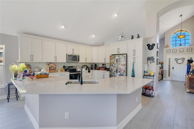 kitchen featuring stainless steel appliances, light countertops, light wood-style floors, and backsplash