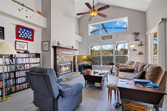 living area featuring lofted ceiling, a brick fireplace, light wood-style flooring, and a ceiling fan