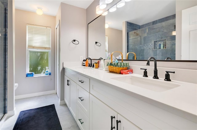 bathroom featuring a sink, a shower stall, baseboards, and double vanity