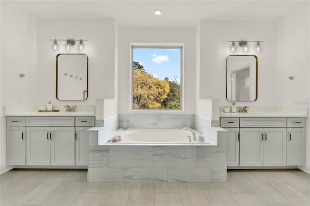 bathroom with vanity and tiled bath