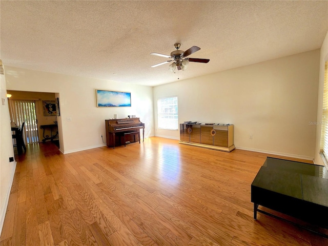 living room featuring ceiling fan, a textured ceiling, and light hardwood / wood-style floors