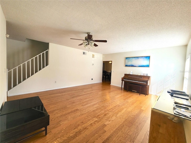 living room featuring a textured ceiling, light hardwood / wood-style flooring, and ceiling fan