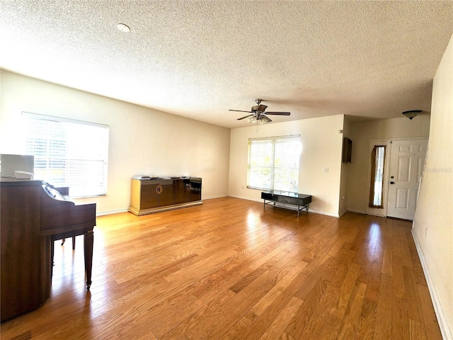 unfurnished living room featuring hardwood / wood-style flooring, a textured ceiling, and ceiling fan