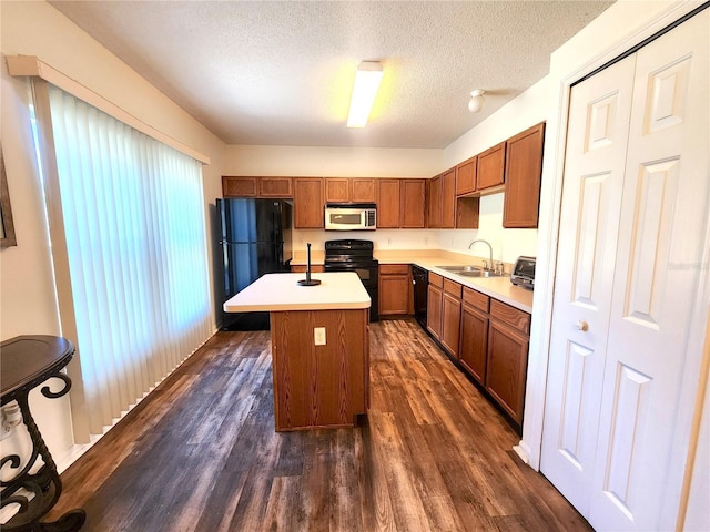 kitchen featuring sink, black appliances, a textured ceiling, a center island with sink, and dark hardwood / wood-style flooring