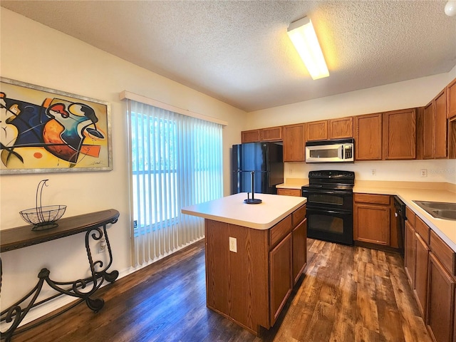 kitchen with sink, a textured ceiling, dark hardwood / wood-style floors, a kitchen island, and black appliances