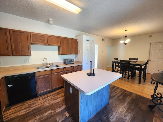 kitchen featuring sink, decorative light fixtures, dark hardwood / wood-style floors, black dishwasher, and a kitchen island