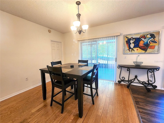 dining room featuring an inviting chandelier, hardwood / wood-style floors, and a textured ceiling