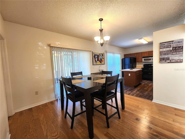 dining room with an inviting chandelier, a textured ceiling, and light hardwood / wood-style floors