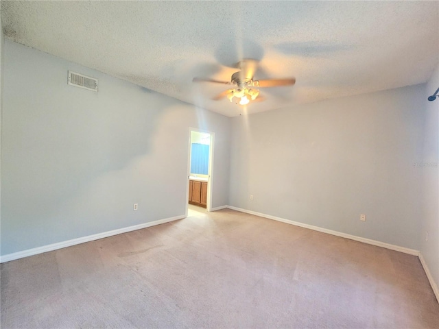 spare room featuring ceiling fan, light colored carpet, and a textured ceiling