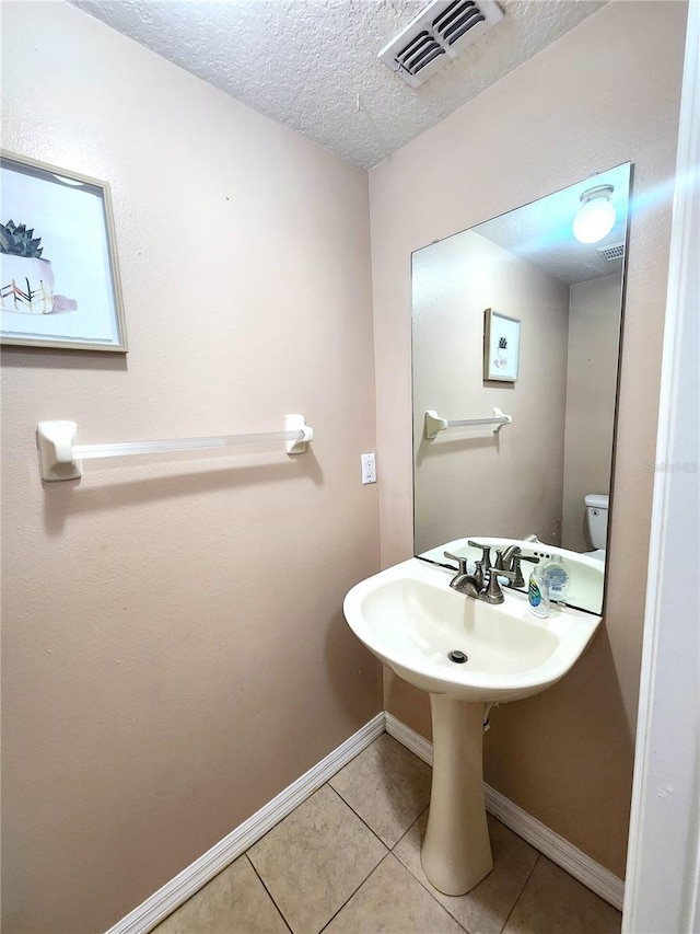 bathroom with a textured ceiling, tile patterned floors, and toilet