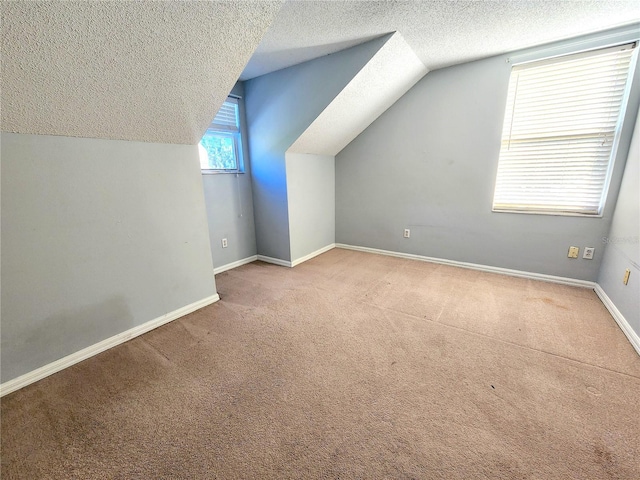 additional living space with light colored carpet, vaulted ceiling, and a textured ceiling