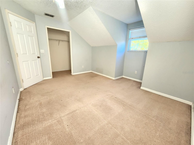 bonus room with light carpet, vaulted ceiling, and a textured ceiling