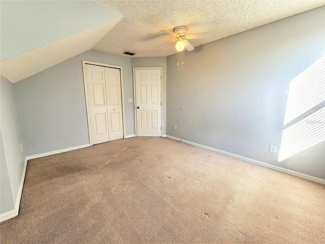 interior space featuring vaulted ceiling, carpet floors, ceiling fan, a textured ceiling, and a closet