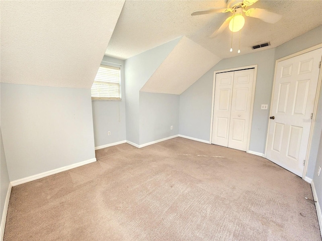 additional living space with light carpet, ceiling fan, vaulted ceiling, and a textured ceiling