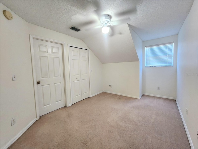 additional living space with light carpet, a textured ceiling, lofted ceiling, and ceiling fan