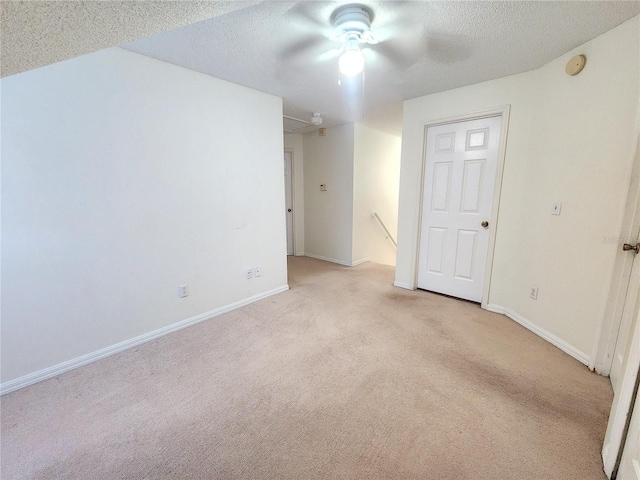 unfurnished room with ceiling fan, light colored carpet, and a textured ceiling