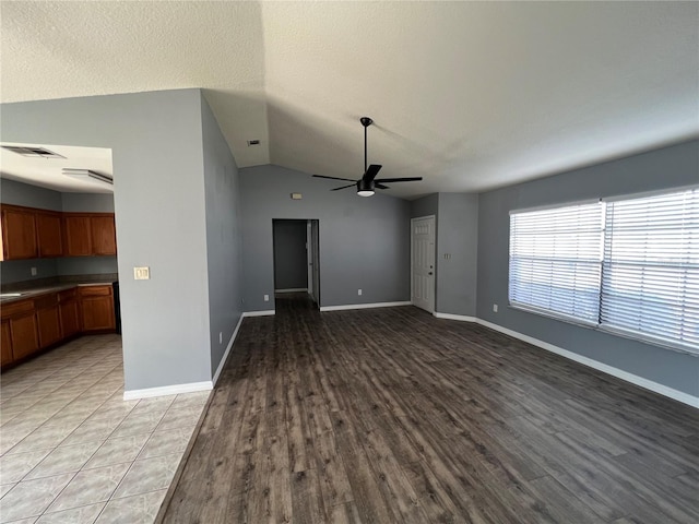 unfurnished living room with lofted ceiling, sink, wood-type flooring, a textured ceiling, and ceiling fan