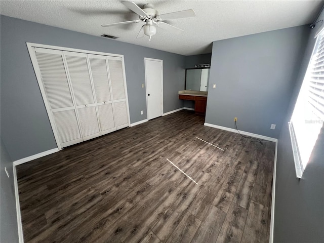 unfurnished bedroom featuring ceiling fan, dark wood-type flooring, a textured ceiling, and a closet