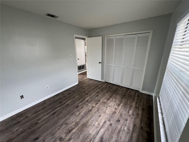 unfurnished bedroom with a closet and dark hardwood / wood-style floors