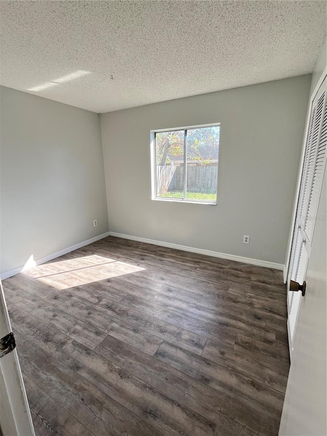 spare room with a textured ceiling and dark hardwood / wood-style flooring