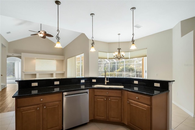 kitchen with vaulted ceiling, dishwasher, sink, dark stone counters, and hanging light fixtures