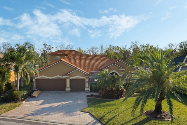 mediterranean / spanish-style home with a garage and a front lawn