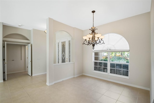 spare room featuring light tile patterned flooring and a notable chandelier