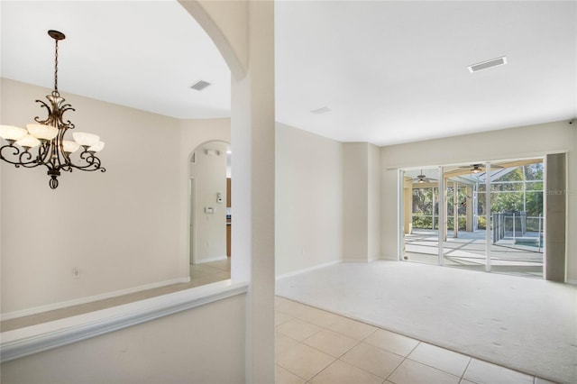 empty room with ceiling fan with notable chandelier and light carpet