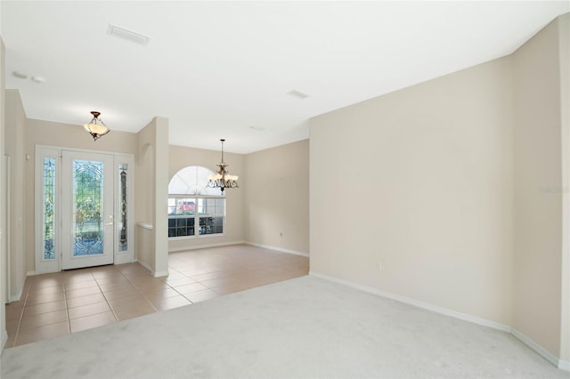 carpeted entryway with a chandelier