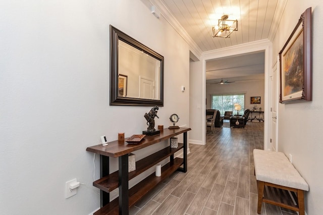 hall with wood-type flooring, a notable chandelier, and crown molding