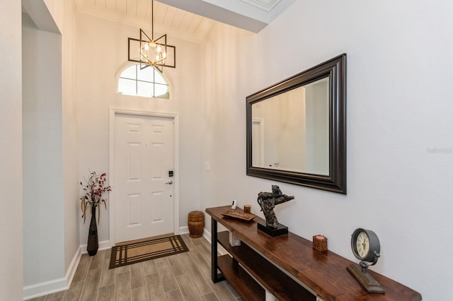 entrance foyer with baseboards, a chandelier, and wood finished floors