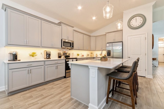 kitchen featuring stainless steel appliances, a breakfast bar area, a sink, and gray cabinetry