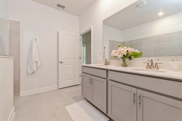 bathroom with visible vents, a sink, baseboards, and double vanity