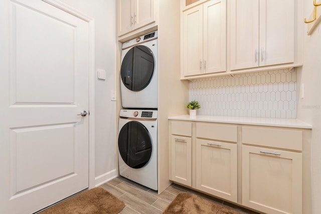 laundry room featuring cabinet space, wood finish floors, and stacked washer and clothes dryer