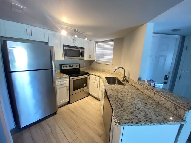 kitchen featuring appliances with stainless steel finishes, white cabinetry, sink, light stone counters, and kitchen peninsula