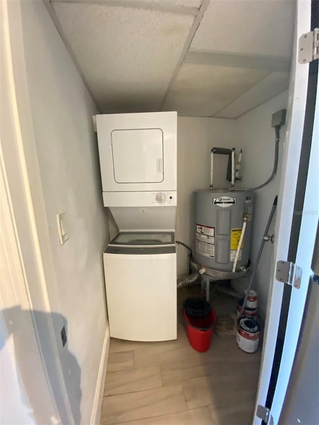 laundry room featuring hardwood / wood-style flooring, stacked washer and dryer, and electric water heater