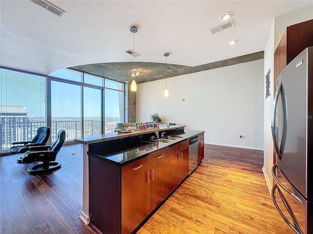 kitchen with decorative light fixtures, light hardwood / wood-style floors, floor to ceiling windows, and appliances with stainless steel finishes