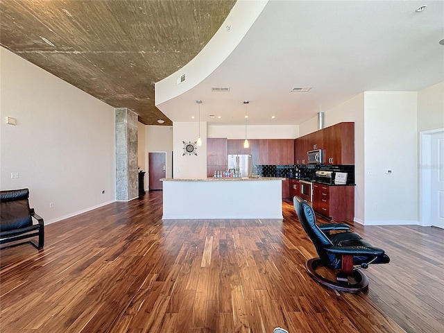 kitchen with appliances with stainless steel finishes, a center island, pendant lighting, and dark wood-type flooring