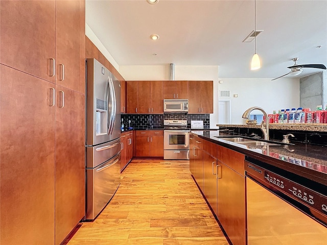 kitchen with sink, decorative light fixtures, stainless steel appliances, light hardwood / wood-style floors, and backsplash