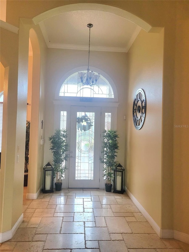 foyer entrance with crown molding, plenty of natural light, an inviting chandelier, and a high ceiling