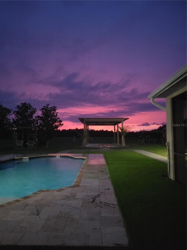 pool at dusk featuring a yard, a patio, and a gazebo