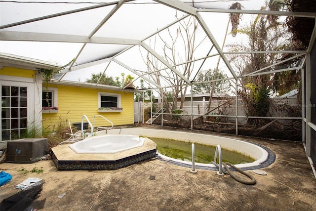 view of pool with an outdoor hot tub and glass enclosure