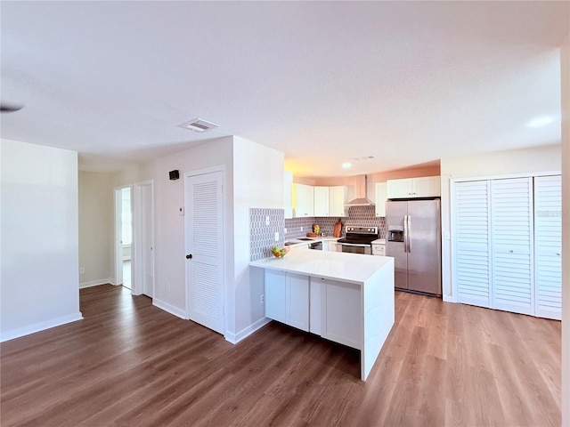 kitchen with hardwood / wood-style flooring, backsplash, stainless steel appliances, white cabinets, and kitchen peninsula