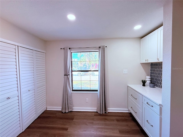 kitchen with a textured ceiling, dark wood-type flooring, and white cabinets