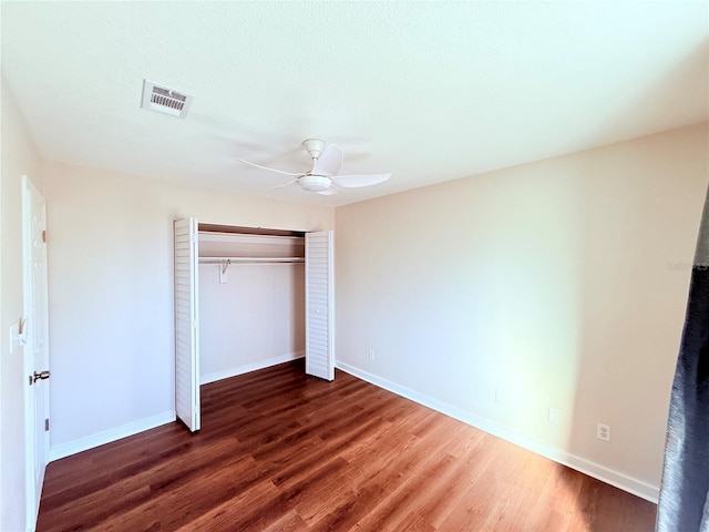 unfurnished bedroom with dark hardwood / wood-style floors, ceiling fan, and a closet