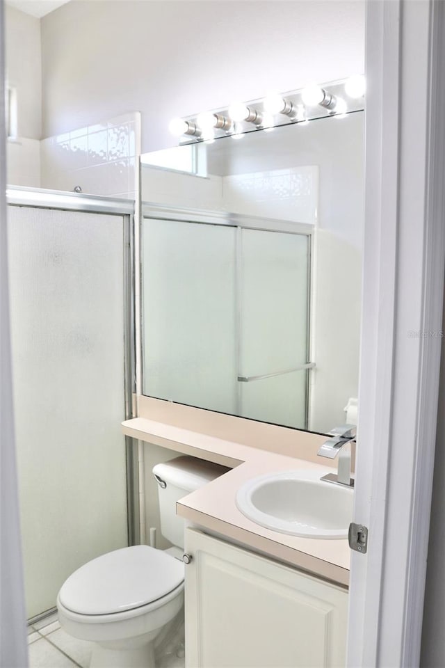 bathroom with tile patterned flooring, a shower stall, toilet, and vanity