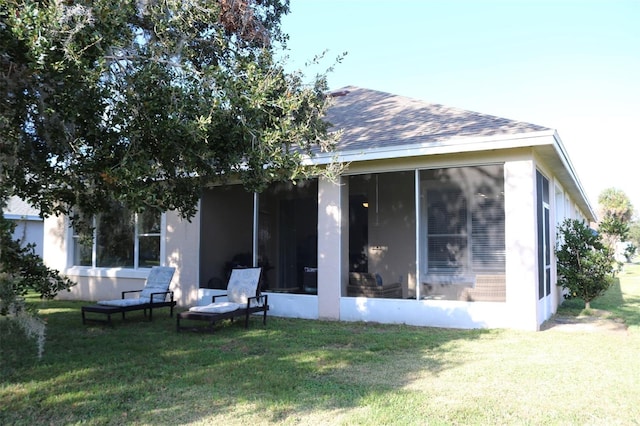 rear view of house featuring a sunroom, a shingled roof, and a yard